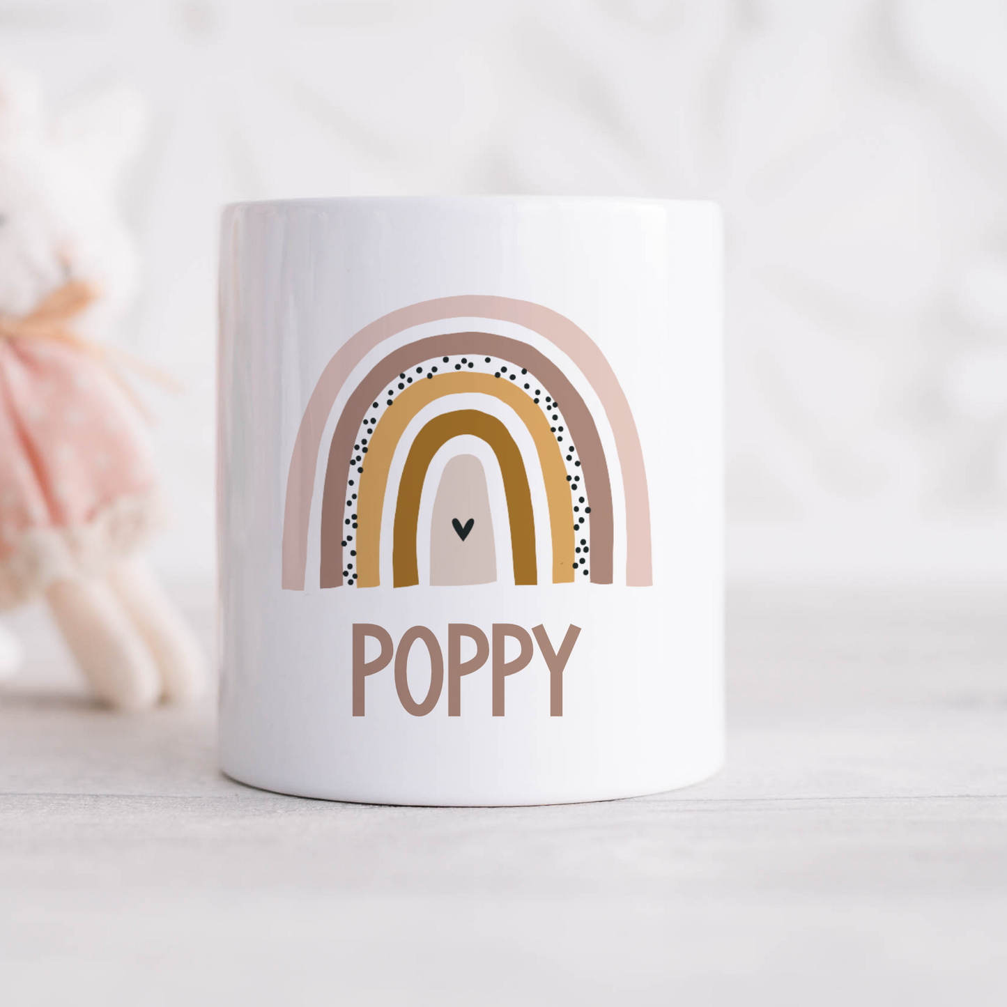 a white coffee mug with a rainbow and a teddy bear