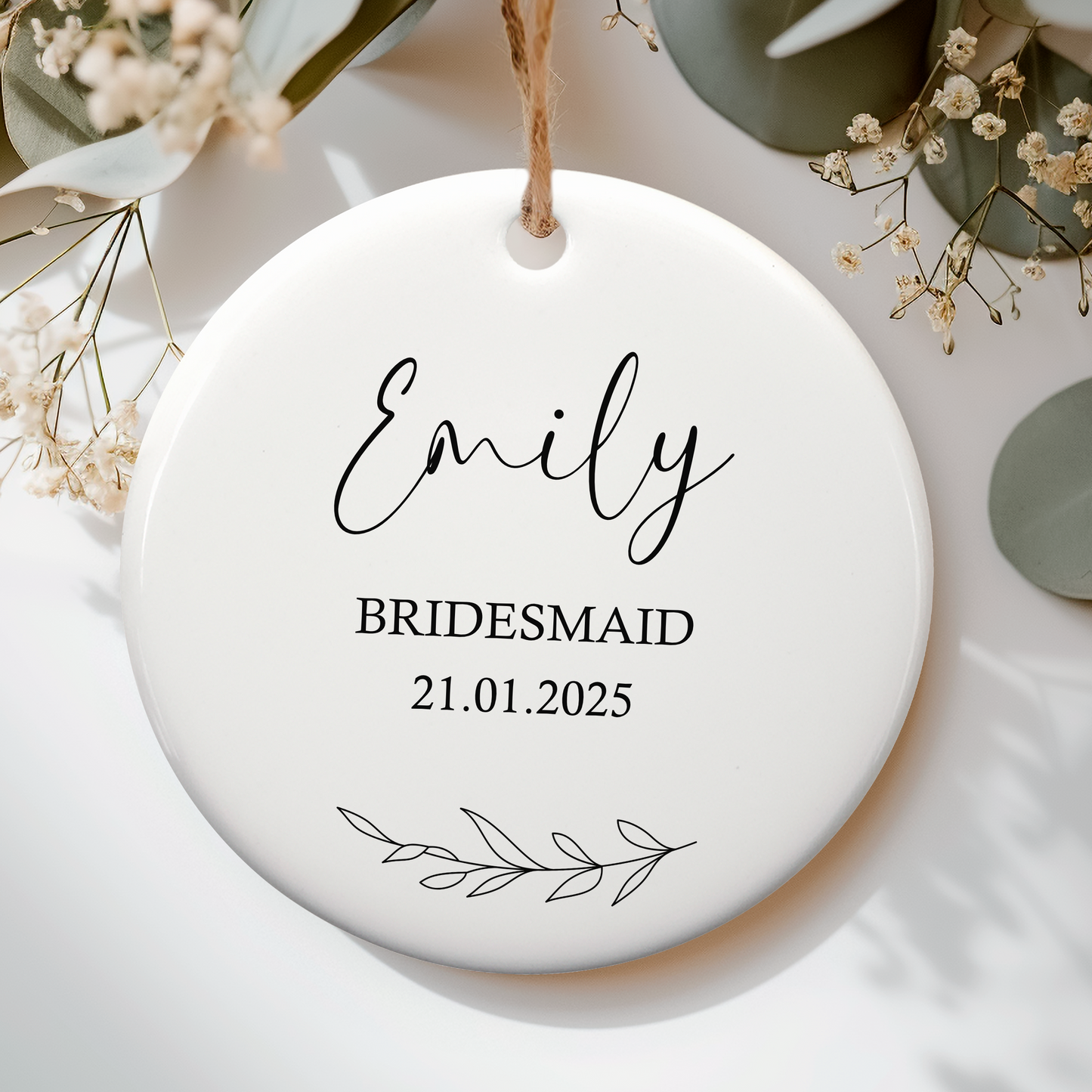 a white ceramic ornament for bridal party, personalised with name and date. Delicate laurel leaf underneath
