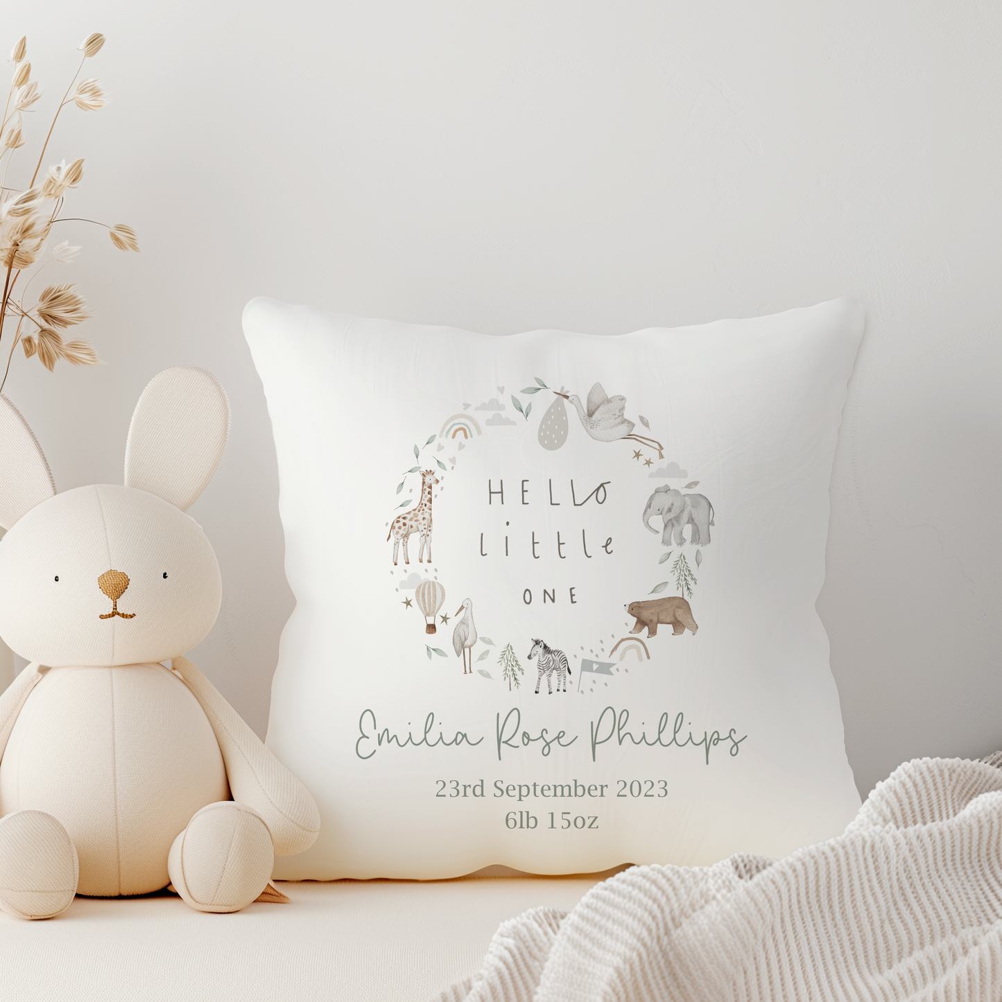 white pillow with hello little one and jungle safari animal wreath. Personalised with name and birth details in green text.