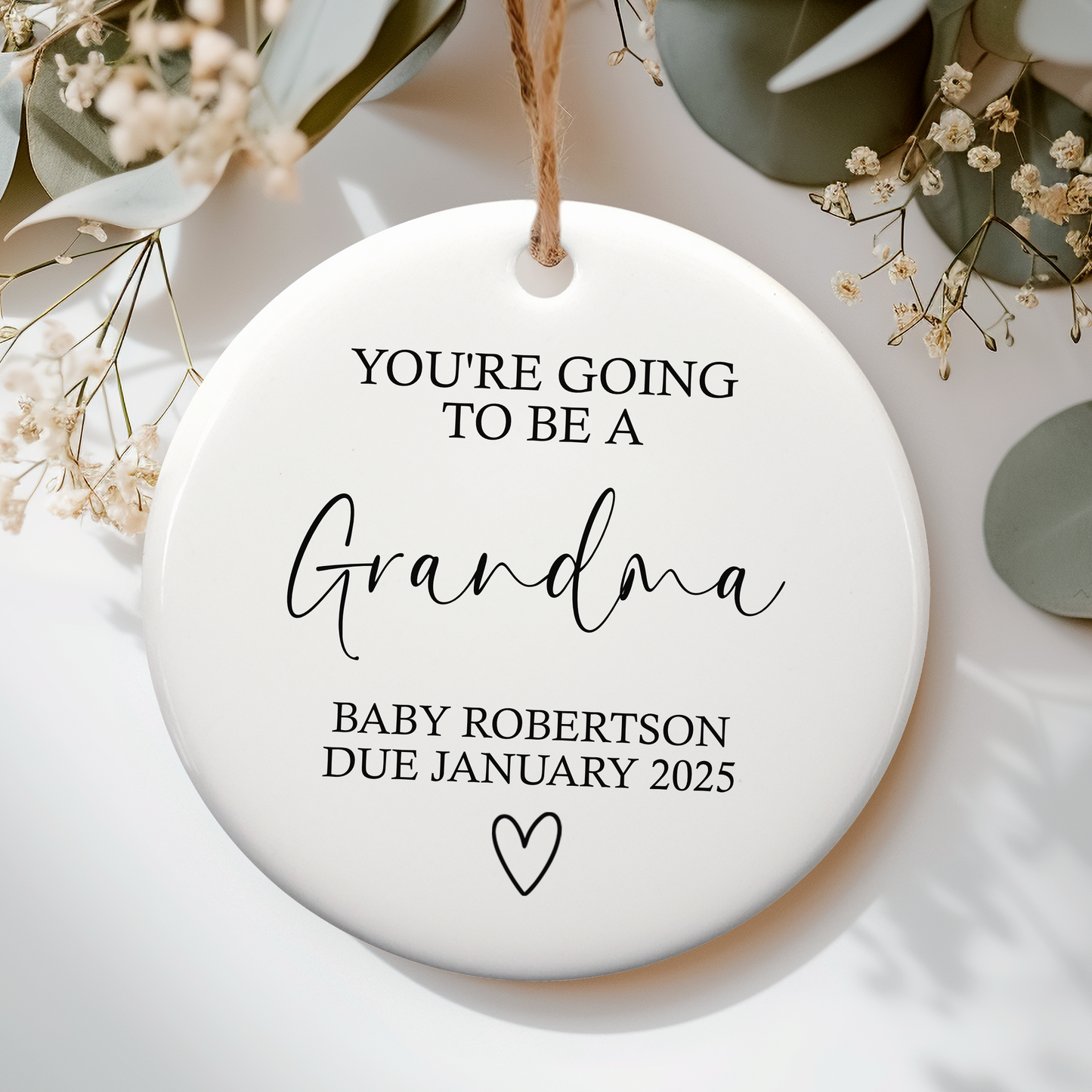 a ceramic ornament with "You're going to be a Grandma" on with baby due date and heart doodle underneath