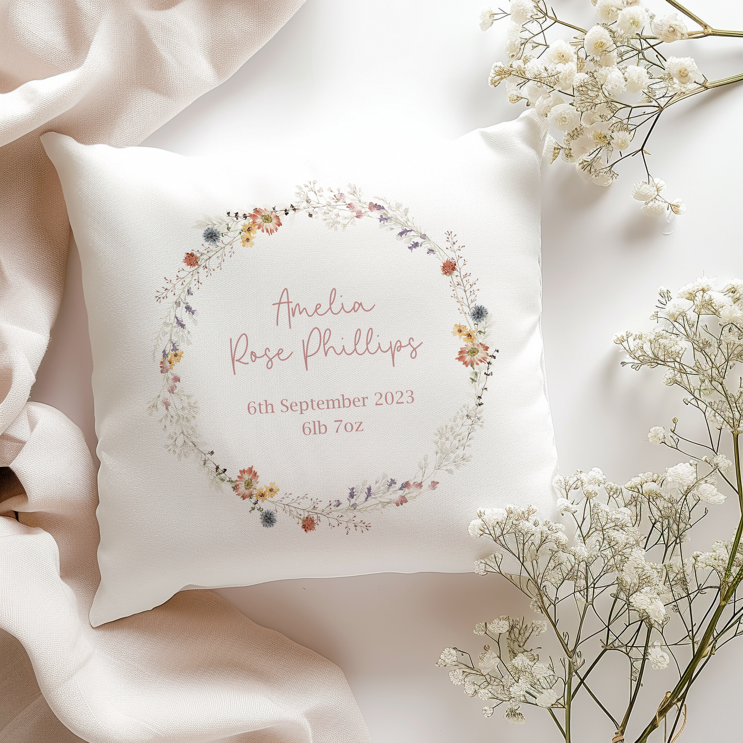 a white pillow with a floral wreath on it, personalied with birth name and date of birth