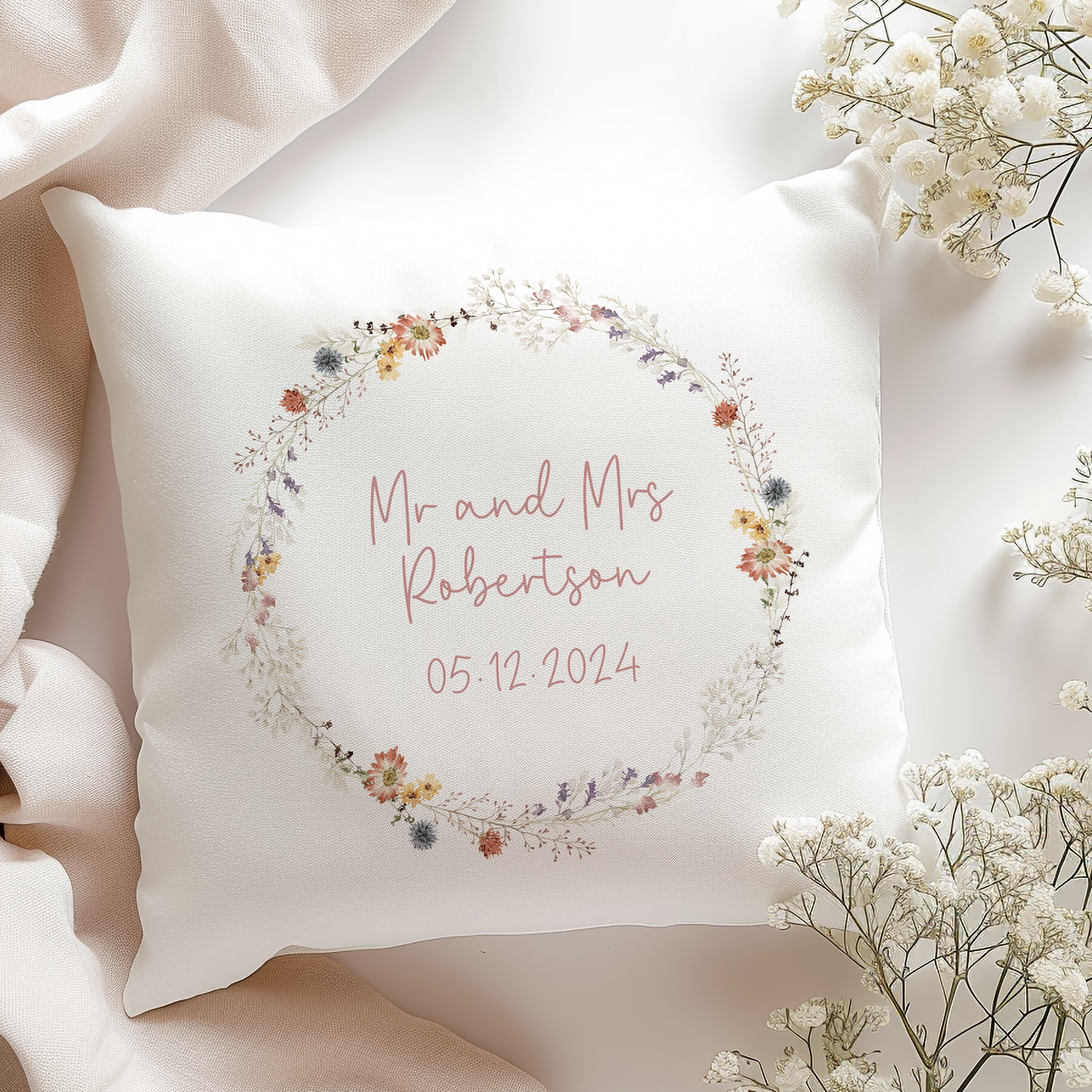 a white pillow with a floral wreath on it, personalised with couples name and wedding date
