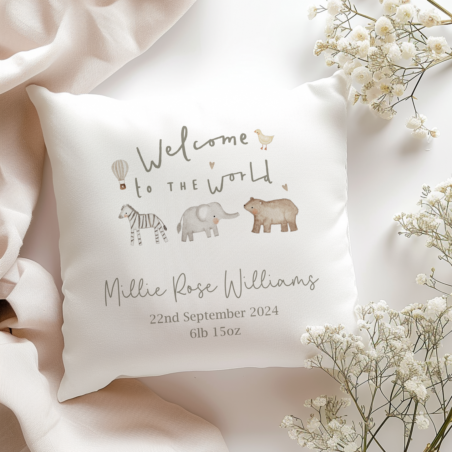 a white pillow with a picture of a baby elephant and jungle safari animals. Personalised with birth name and date in green font.