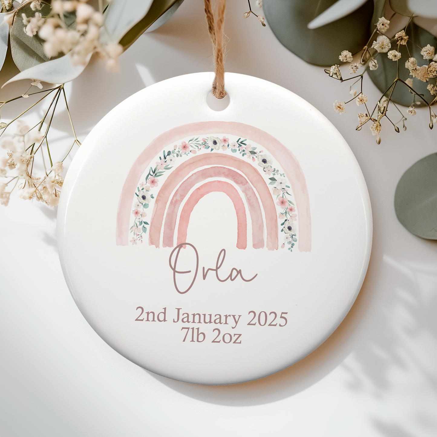 a ceramic ornament with a pink floral rainbow on it, personalised with name and birth details
