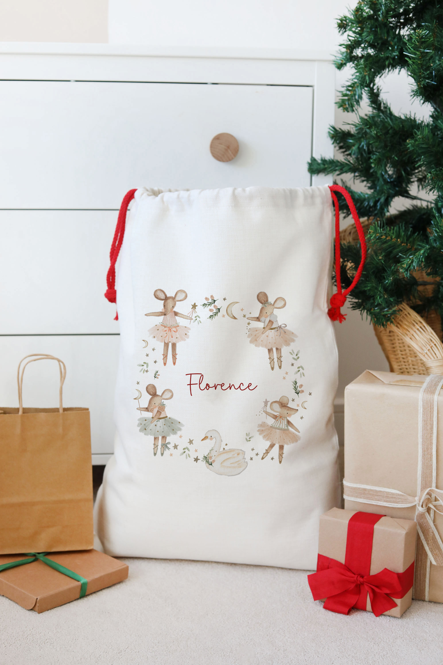 White drawstring bag with decorative elements and 'Florence' text, placed next to Christmas presents and a tree.