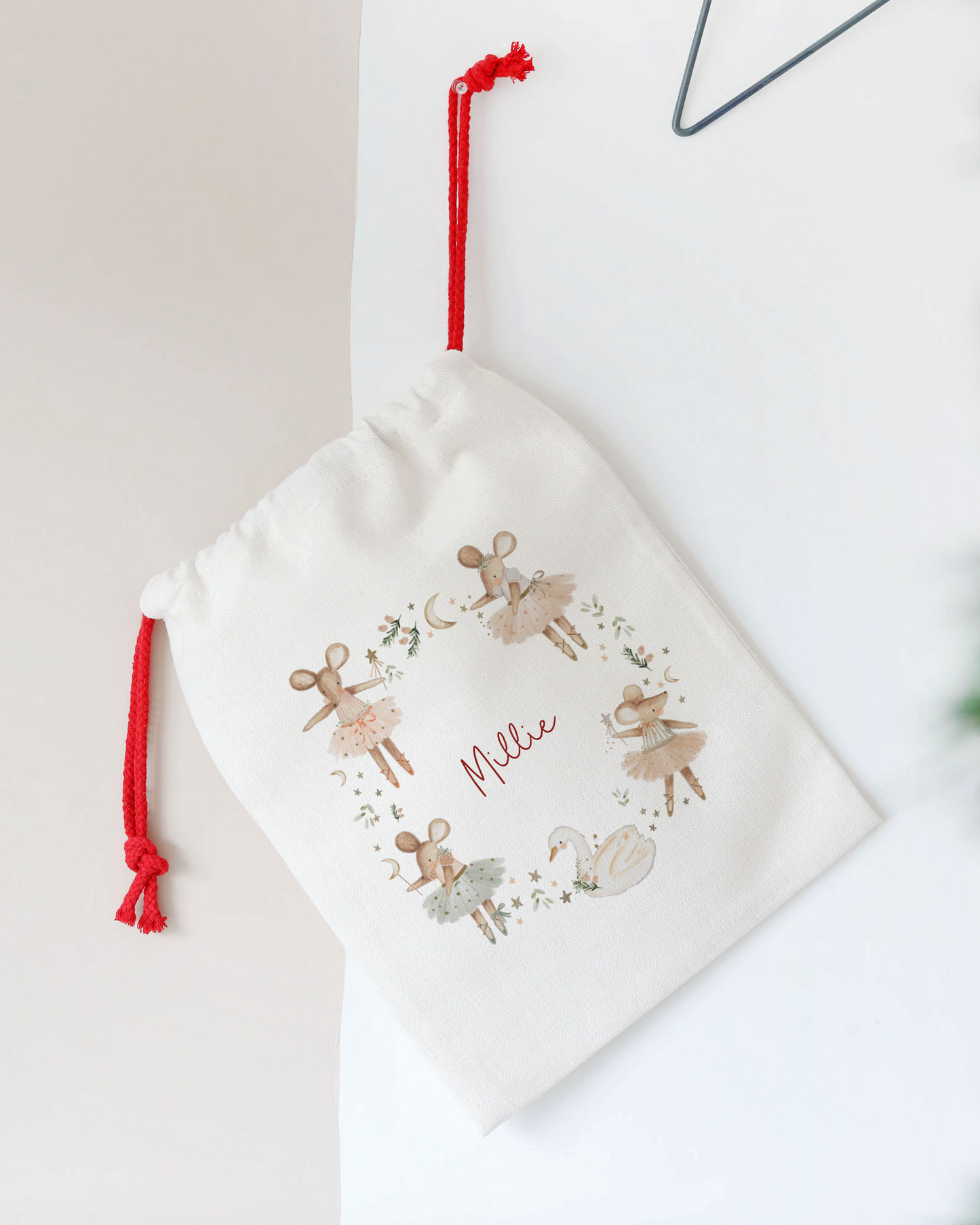White drawstring bag with reindeer design and 'Feliz' text, hanging on a star-shaped hook.