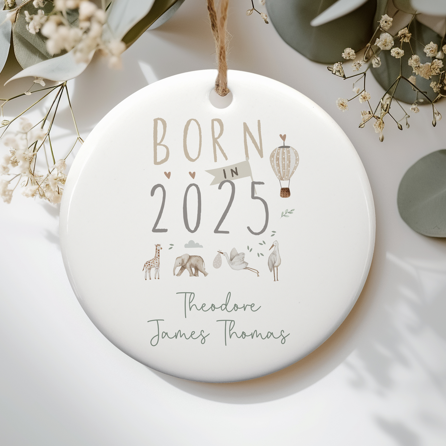 a ceramic ornament with born in 2025 text, illustrated with jungle safari animals and a hot air balloon