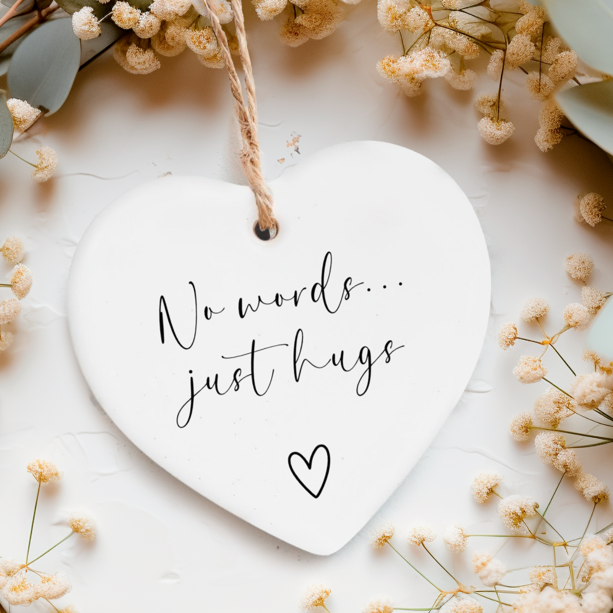 White ceramic heart ornament with twine with the words "No words...just hugs" on and a small heart doodle underneath.