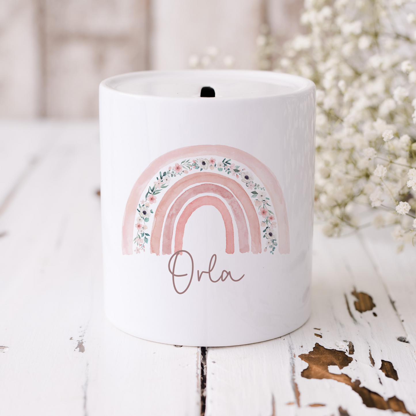 White ceramic money box with pink floral rainbow, personalised with name in script font.