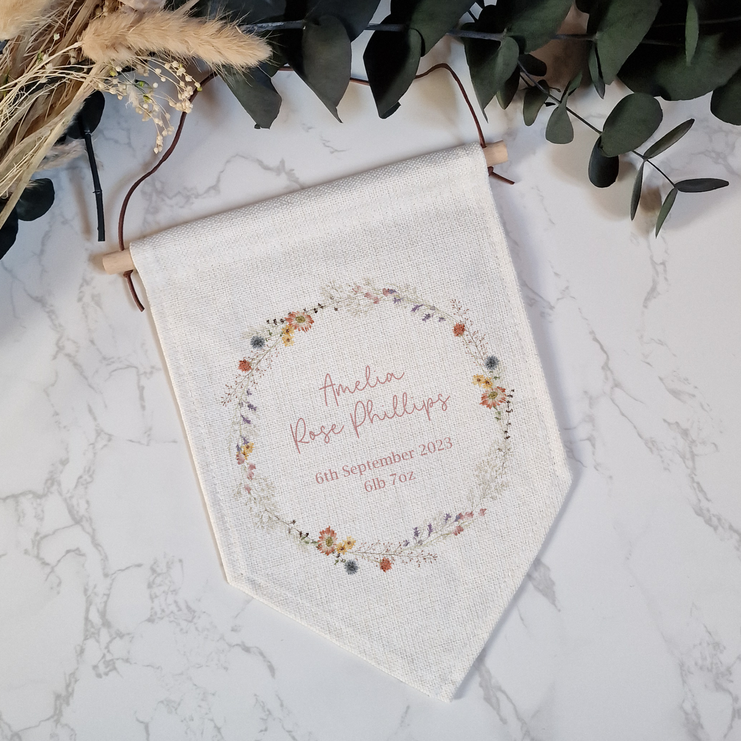 Off white linen pennant flag with wildfloweer wreath illustration. Personalised with name and birth details.