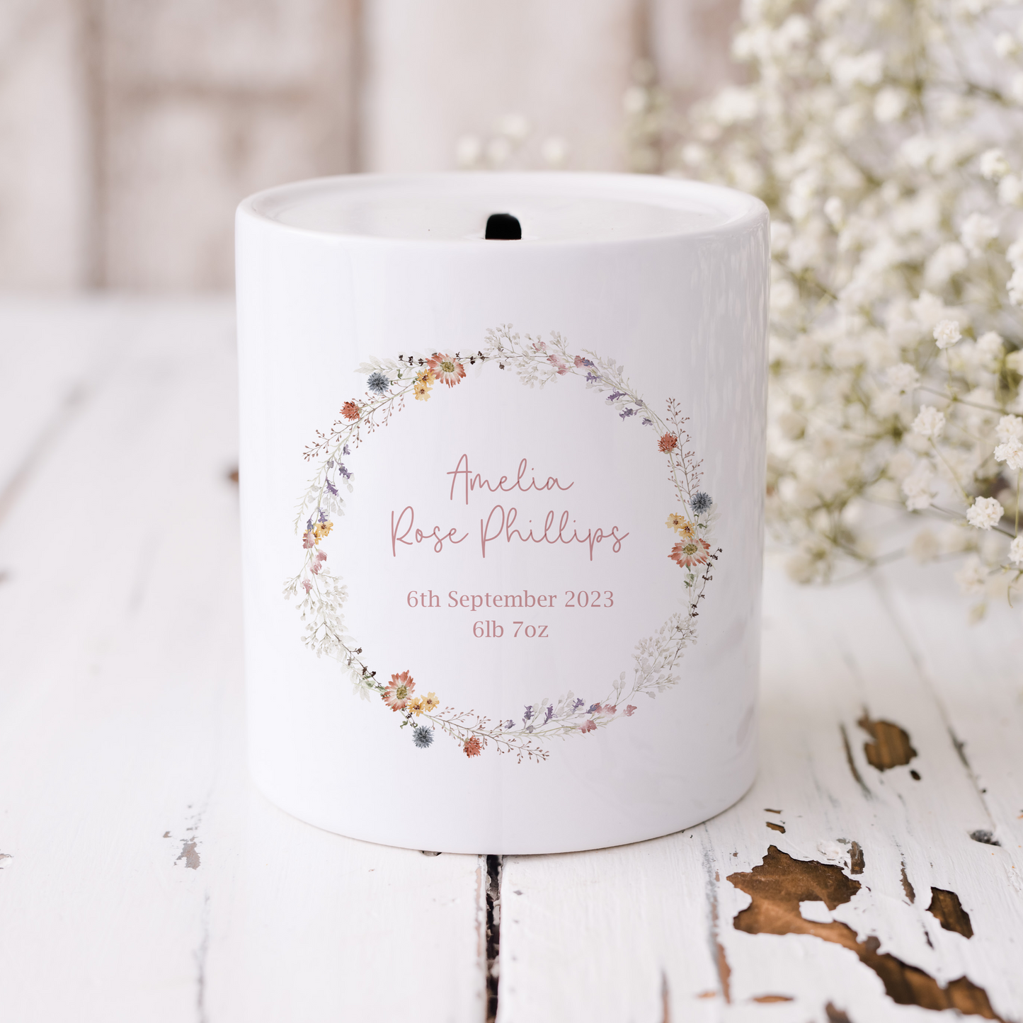 White ceramic money box with wildflower wreath, personalised with birth name and date and weight.
