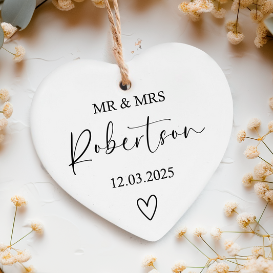 a white ceramic heart with a couple's names and wedding date on it