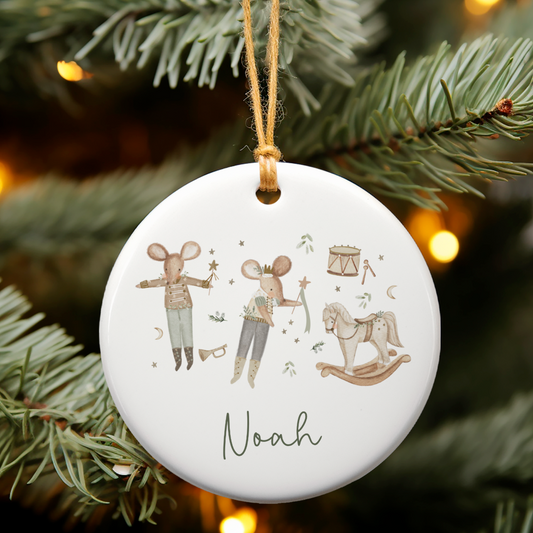 Decorative Christmas ornament with Nutcracker mice 'Noah' on a tree branch with lights in the background