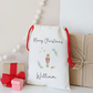 White gift sack with 'Merry Christmas' and a nutcracker design, surrounded by small gifts on a light background.