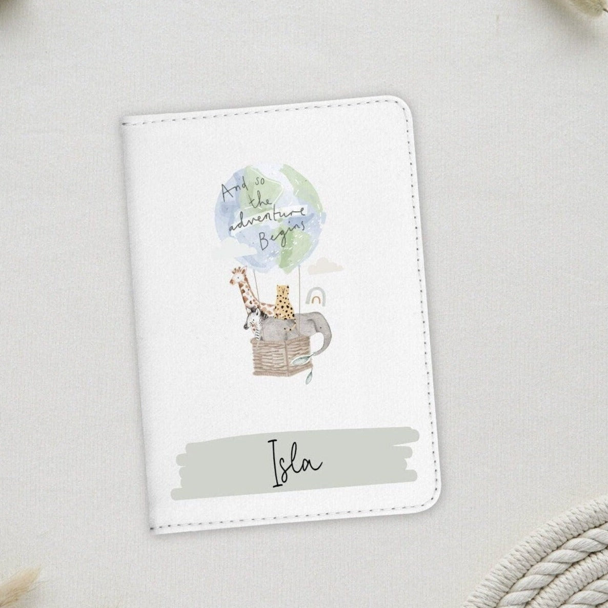 White passport holder with safari animals in hot air balloon illustration. Banner at bottom with name.