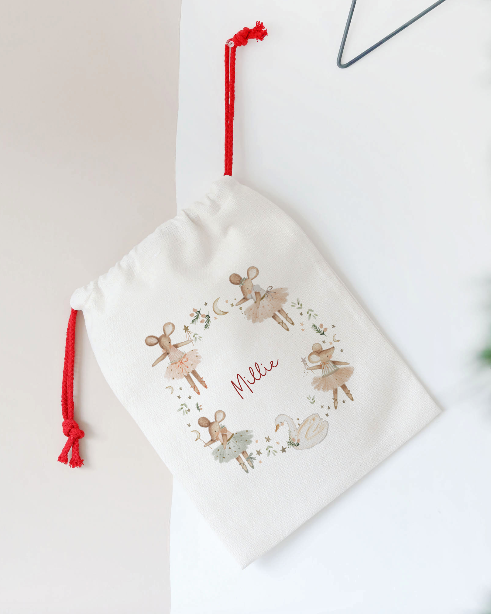 White drawstring bag with reindeer design and 'Feliz' text, hanging on a star-shaped hook.