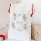 White drawstring bag with decorative elements and 'Ottie' text, placed on a light surface with gift boxes in the background.