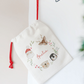 Decorative pouch with illustrations and text hanging on a white wall.