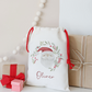 Decorative gift bag with 'Oliver' printed on it, surrounded by small wrapped gifts on a light background.