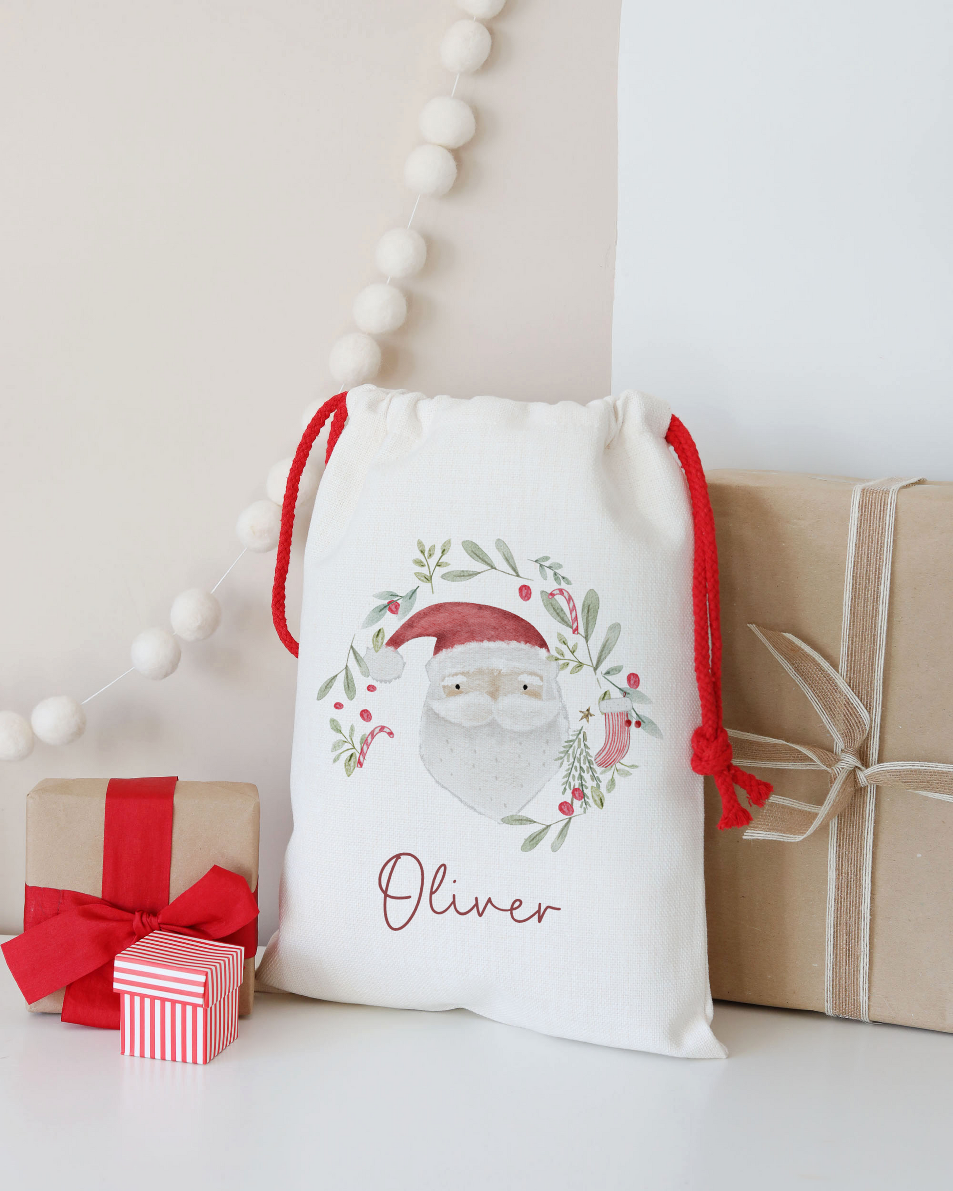 Decorative gift bag with 'Oliver' printed on it, surrounded by small wrapped gifts on a light background.