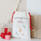 Personalized gift bag with red drawstring, small wrapped gifts, and decorative elements on a light background