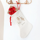 White Christmas stocking with festive mice and swan, hanging on a wooden hanger against a white background.