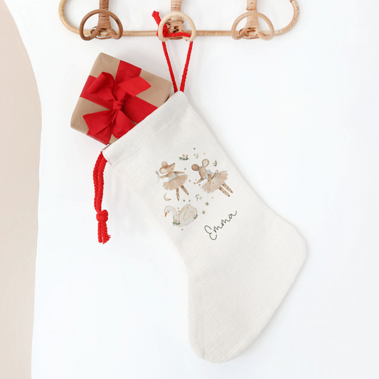 White Christmas stocking with festive mice and swan, hanging on a wooden hanger against a white background.