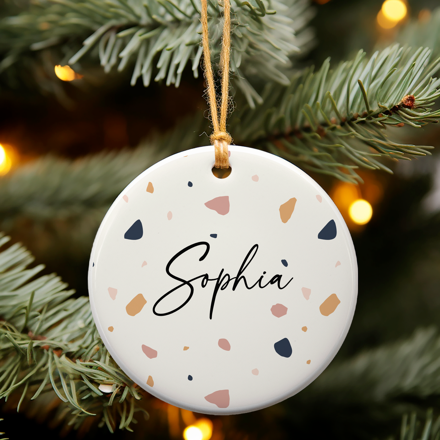 White ceramic oranment with terrazzo print, personalised with name in a handwritten script font.