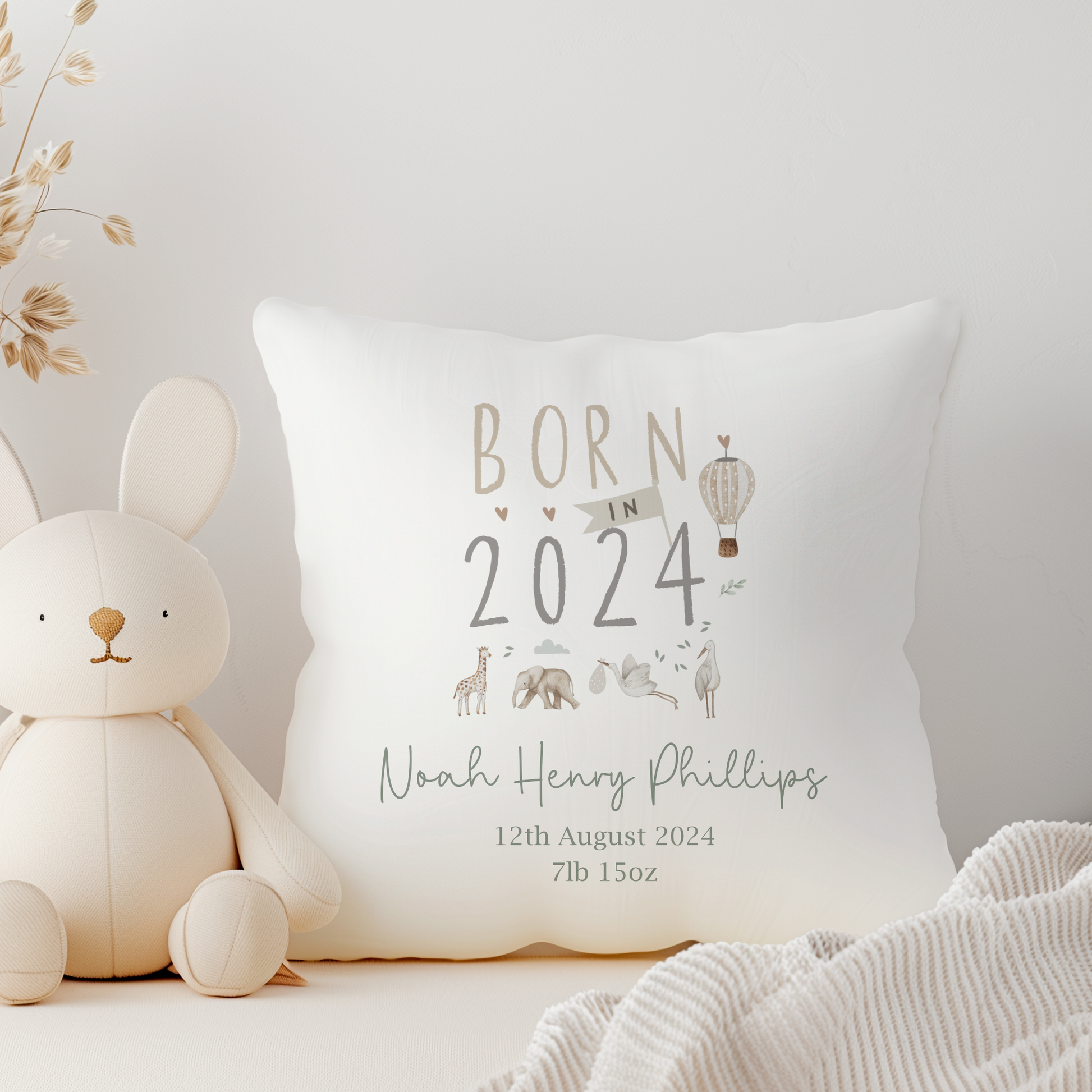 white pillow with born in 2024 text and hot air balloon illustration, personalised with name in green font.