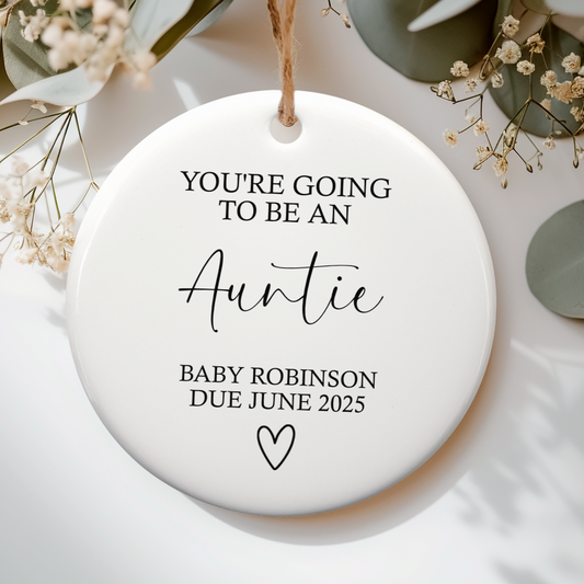 White ceramic ornament with the text "you're going to be an auntie" and baby's due details, with cute heart doodle underneath.