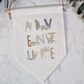 a wall hanging with a plant and a banner