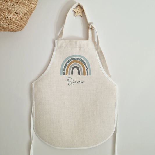 Beige apron with blue rainbow design personalised with name