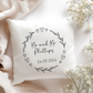a pillow with a floral heart wreath and personalised with couples name and wedding date in black text.