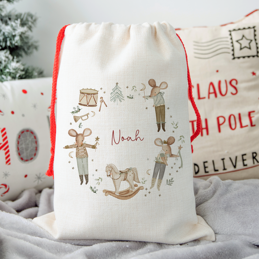 Decorative Christmas sack with festive nutcracker mouse design and personalised name on a soft surface.