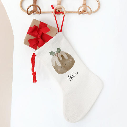 White Christmas stocking with christmas pudding design, hanging on a wooden rack.