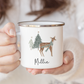 A lady holding a white enamel mug with festive deer and trees illustration, personalised with name in black script font.