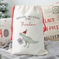 Off white linen santa sack with T-rex carrying a present. Text of special delivery for Theodore
