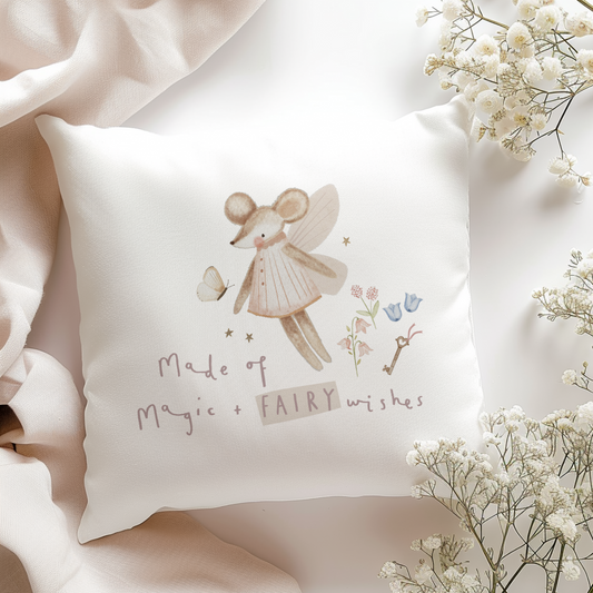 Decorative pillow with fairy mouse design and text, surrounded by white flowers on a light background