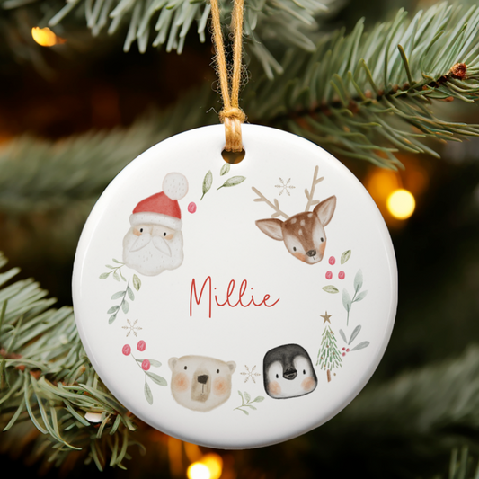 White ceramic christmas ornament with festive animals and santa clause and decorative foliage. Personalised with name in red script font.