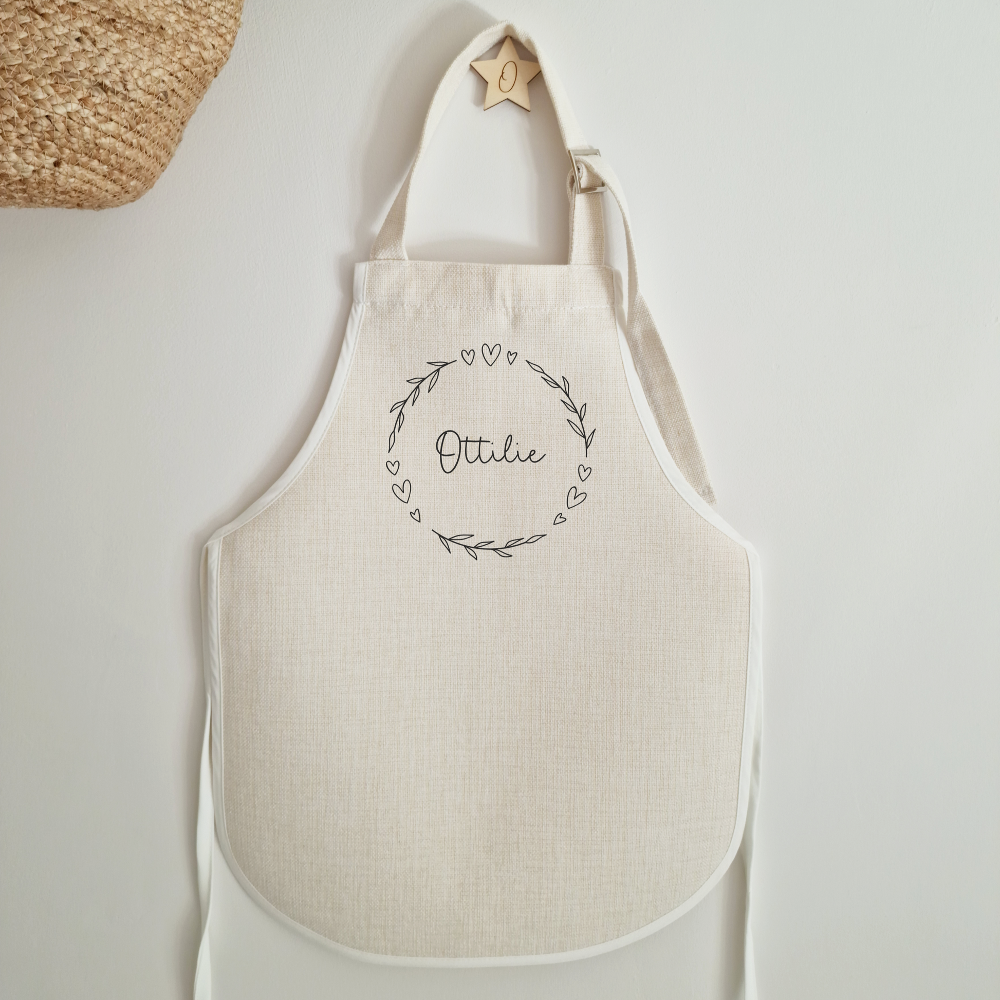 Off white linen-like childs apron, personalised with name in the centre of a floral heart wreath