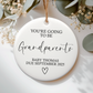 White ceramic ornament with you're going to be grandparents text. Flat lay on a botanical neutral background