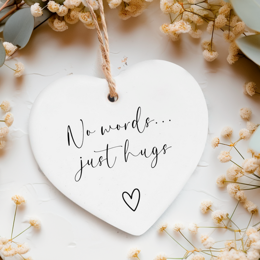 White ceramic heart ornament with twine with the words "No words...just hugs" on and a small heart doodle underneath.