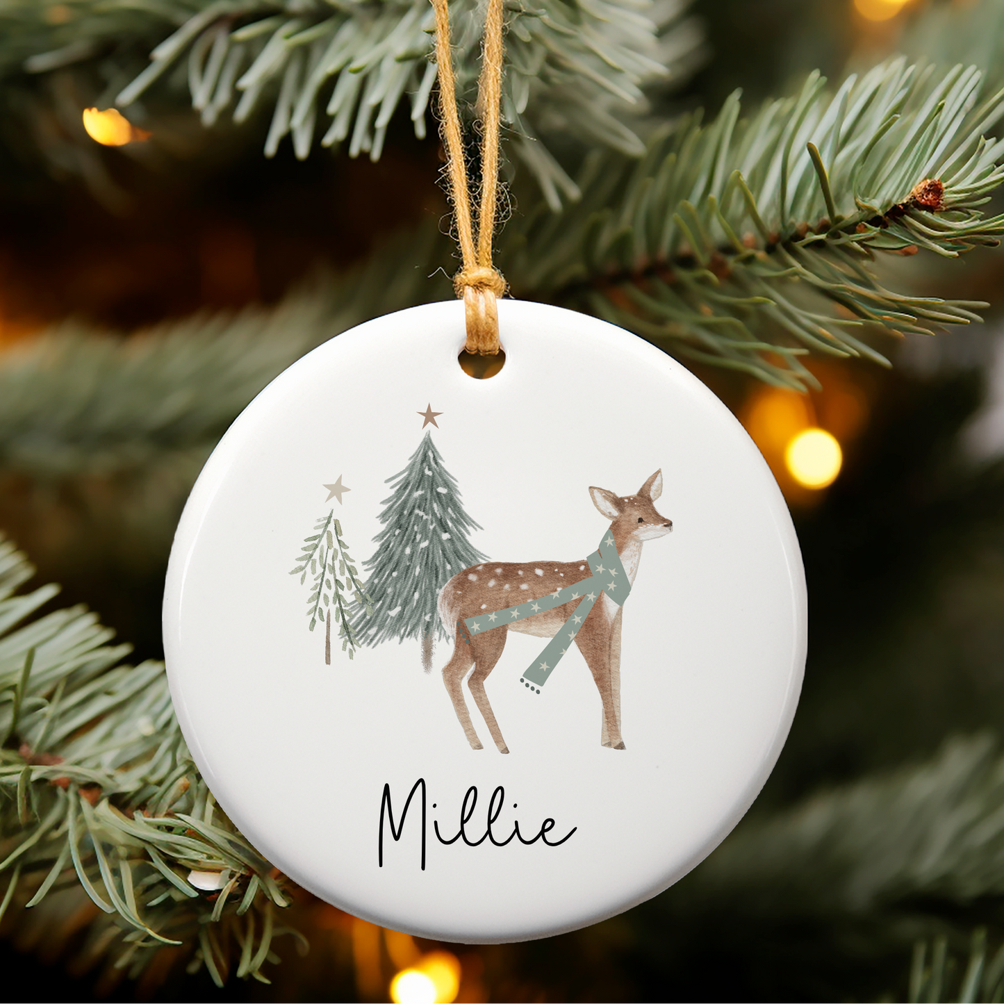 Decorative Christmas ornament with a deer design and 'Millie' text, hanging on a tree.