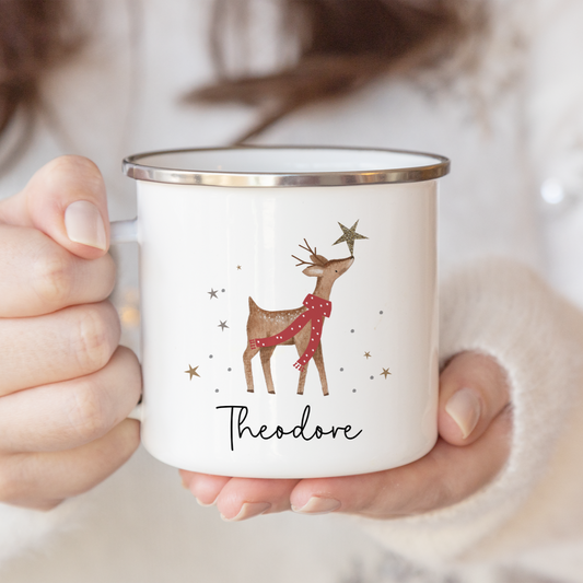 Person holding a mug with a reindeer design and 'Theodore' text.
