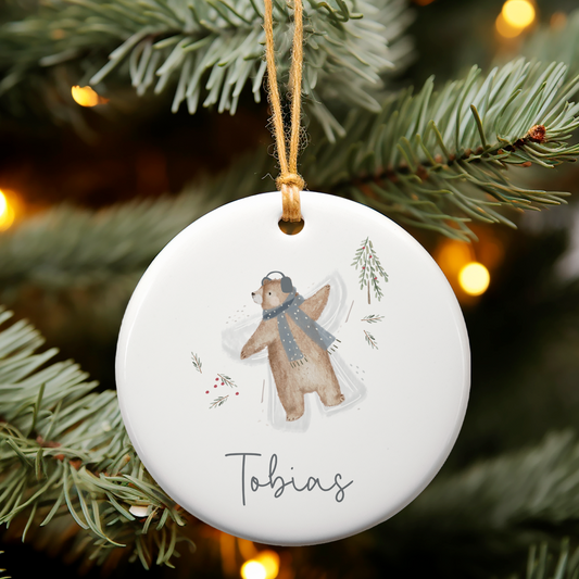 Decorative Christmas ornament with a bear design and 'Tobias' text, hanging on a tree.