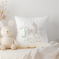 White plush bunny toy next to a pillow with unicorn design on a light gray background